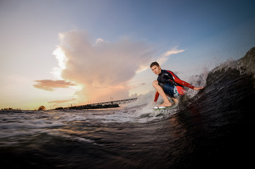 Side view active male wakeboarder riding on the bending knees on the board