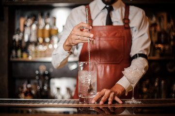 Bartender stirring an ice cubes in the cocktail