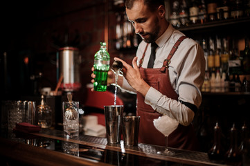 Bartender pourring an achohol from the measuring cup into a steel shaker