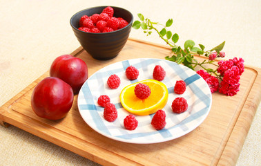 Photo of raspberries with orange,nectarine and roses.