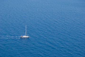 Sailing boat going motorized in the middle of the blue and tranquil sea