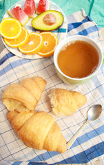 Morning flat lay with croissants,cup of tea ans fruits.