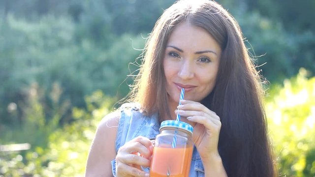 Woman drinks smoothies or orange fresh outdoors.