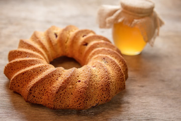 A homemade cake and a honey bank on a rough, simple wooden village table.
