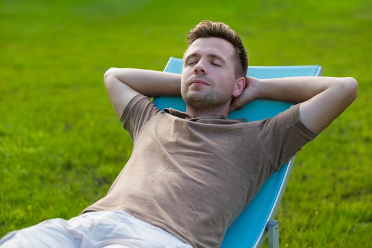 Man Sitting And Resting In Chair On Green Lawn