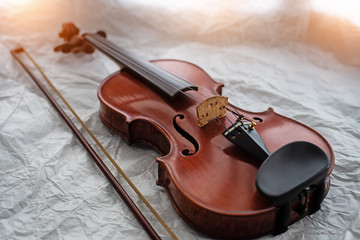 Fototapeta na wymiar The wooden violin and bow put on grunge surface background,warm light tone,blurry light around.
