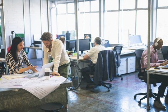 Business colleagues discussing over laptop