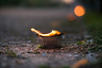 Macro shot of lit candle burning with soft glowing flame and smoke on evening background. Candle path at the park close to the seaside during the Night of ancient lights.