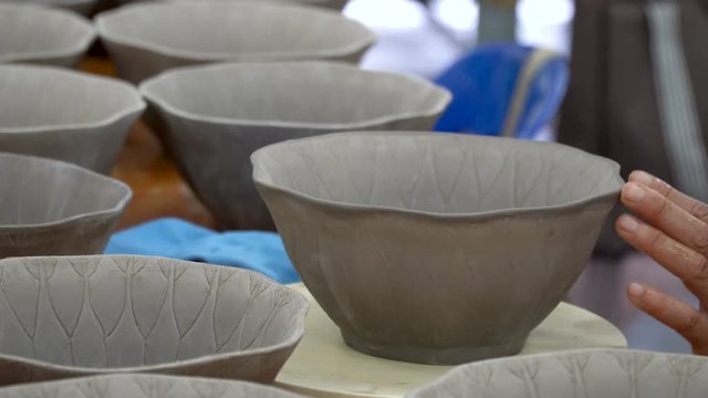 traditional pottery making, close up of potter's hands shaping a bowl on the spinning by clay