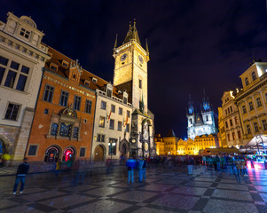 Thousands of tourists walking in spring night on the Old Town square with Tyn Church.