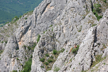 Fearless mountain climber with equipment hanging over dangerous ravine performing stunts on slack line. Daredevil travelers enjoying difficult climbing routes  