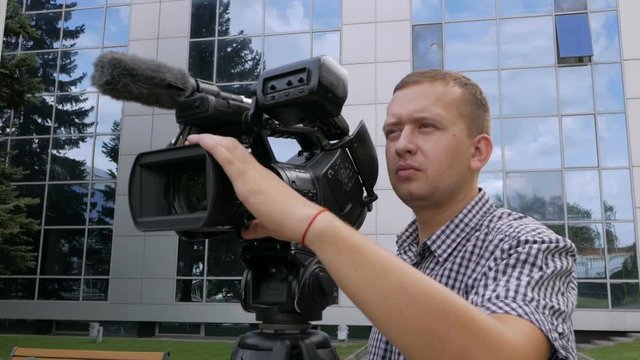 The TV operator removes the video with a professional video camera, which stands on a tripod.