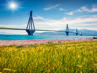 Sunny morning scene of Rion-Antirion Bridge. Colorful spring view of the Gulf of Corinth, Greece, Europe. Beauty of countryside concept background. Artistic style post processed photo.