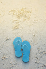 Fototapeta na wymiar blue sandals on sands and beach - vacation concept