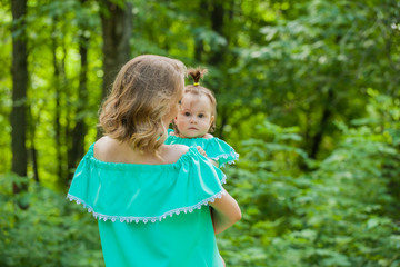 A young mother and daughter in identical dresses for a walk. The child is afraid