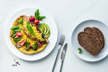 top view of homemade omelette and bread for breakfast on white marble surface