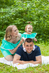 a family of three people on a walk in the park. Picnic on the grass