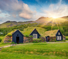 Fototapeta na wymiar Tipical view of Icelandic turf-top houses. Wonderful summer sunrise in the Skogar village, south Iceland, Europe. Beauty of countryside concept background.