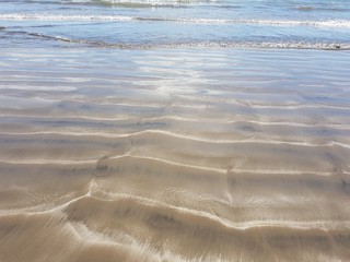 heller Stand mit wellenförmigem glitzernden Sand