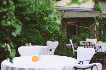 stylish cafe with white tablecloths and a background of green bushes. free tables.