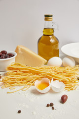  close up view of arranged ingredients for cooking italian pasta on white tabletop