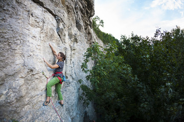 A strong girl climbs the rock.