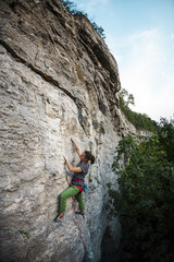A strong girl climbs the rock.
