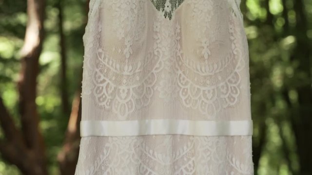 Vintage wedding dress hanging in the forest.