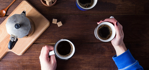 Two people drinking coffee, wooden table, top view, hands, long banner