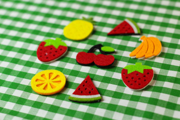 Fruit placement on white green cloth, grapes,bananas, peaches,watermelon, strawberry, orange, felt. Needlework with felt.