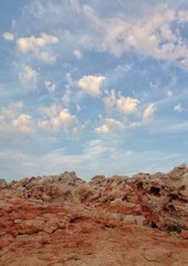Red stones and a gentle blue sky with clouds