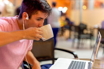 Mixed race studen drinking coffee while working on computer lapt