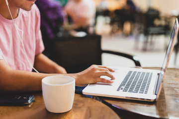 Selected focus mug of coffee on the table with young man working