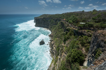 cliff steep with waves and surf in uluwatu temple blue water in bali indonesia