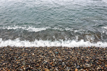 waves of the blue sea on a pebble beach. small pebble stones by the sea.