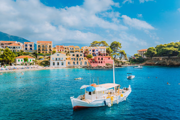 View of beautiful bay of Assos village with fishing boat at anchor in front and clouds in background, Kefalonia island, Greece - Powered by Adobe