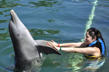 Woman holding and getting a kiss from a dolphin.