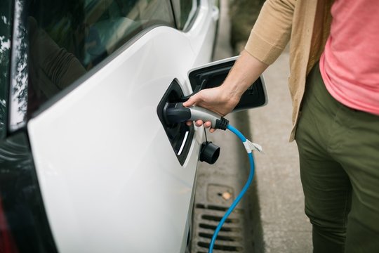 Man charging electric car at charging station