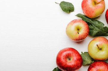 Ripe red and yellow apples with green leaves on white background. Good harvest. Copy space
