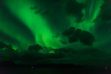 Fototapeta na wymiar norwegian aurora borealis with mountains and water, view from hurtigruten ship boat, norway, europe, green northern lights