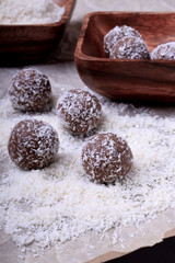 Ball-shaped sweets sprinkled with coconut flakes on a piece of parchment paper