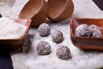 Ball-shaped sweets sprinkled with coconut flakes on a piece of parchment paper