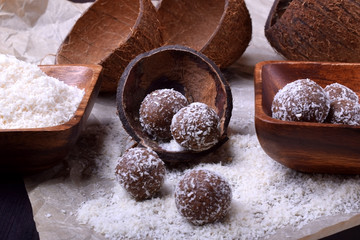 Ball-shaped sweets sprinkled with coconut flakes on a piece of parchment paper