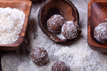 Ball-shaped sweets sprinkled with coconut flakes on a piece of parchment paper