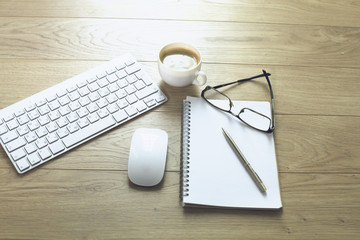 office desk table with computer keyboard, notebook with pen and coffee cup on desk