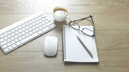 office desk table with computer keyboard, notebook with pen and coffee cup on desk