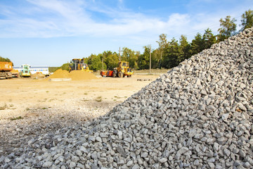 A fine gray graphite gravel is piled high on the background of machinery and wood. Road repair.