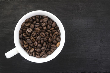 A cup of coffee beans on a black background. Free place for the inscription.