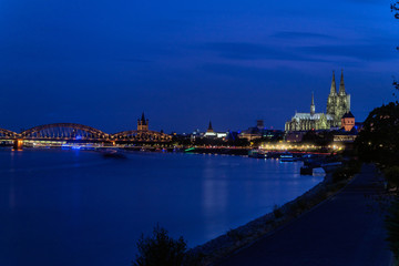 Naklejka premium Dome of the City of Cologne, Gemany on the right, Rhine River on the left at blue hour
