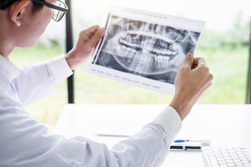 Image of male doctor or dentist holding and looking at dental x-ray